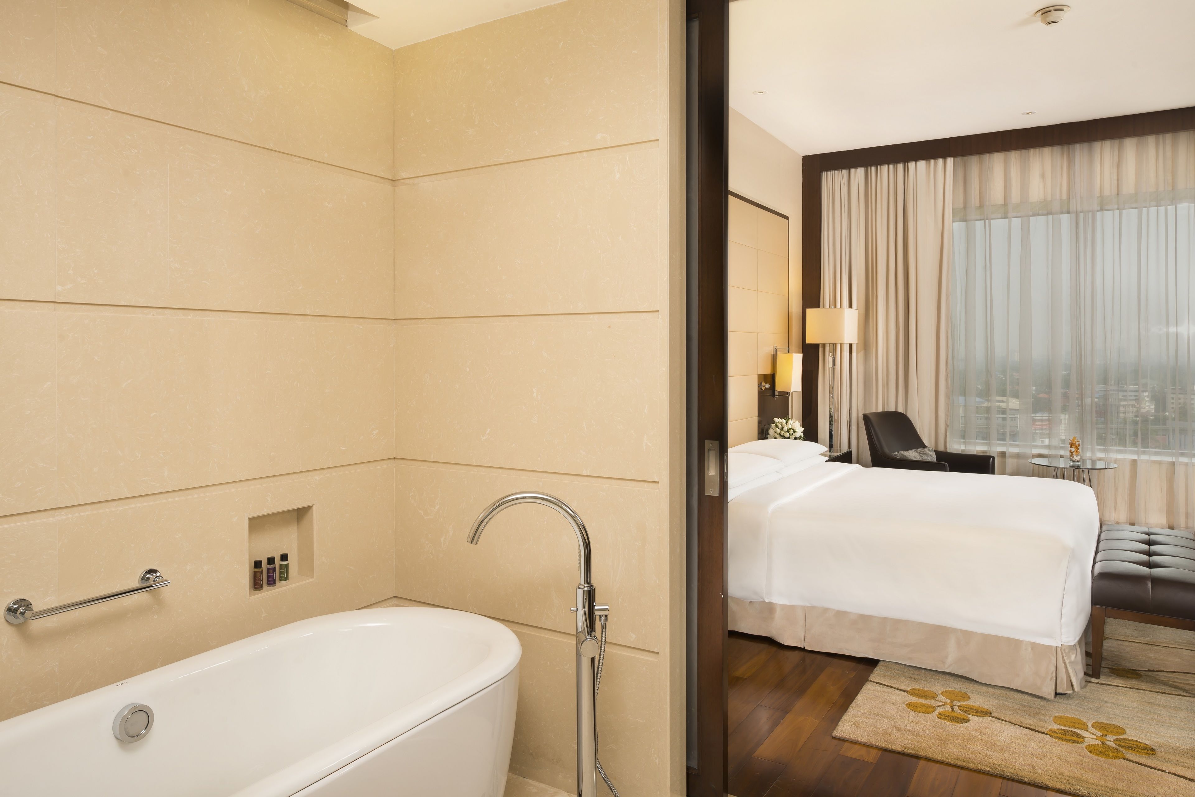A hotel bathroom with a bathtub, a shower, and a small shelf with toiletries.