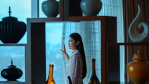 A room with a large window, shelves with various decorative items, and a person standing near the window. - Kochi Marriott Hotel (Kanayannur)
