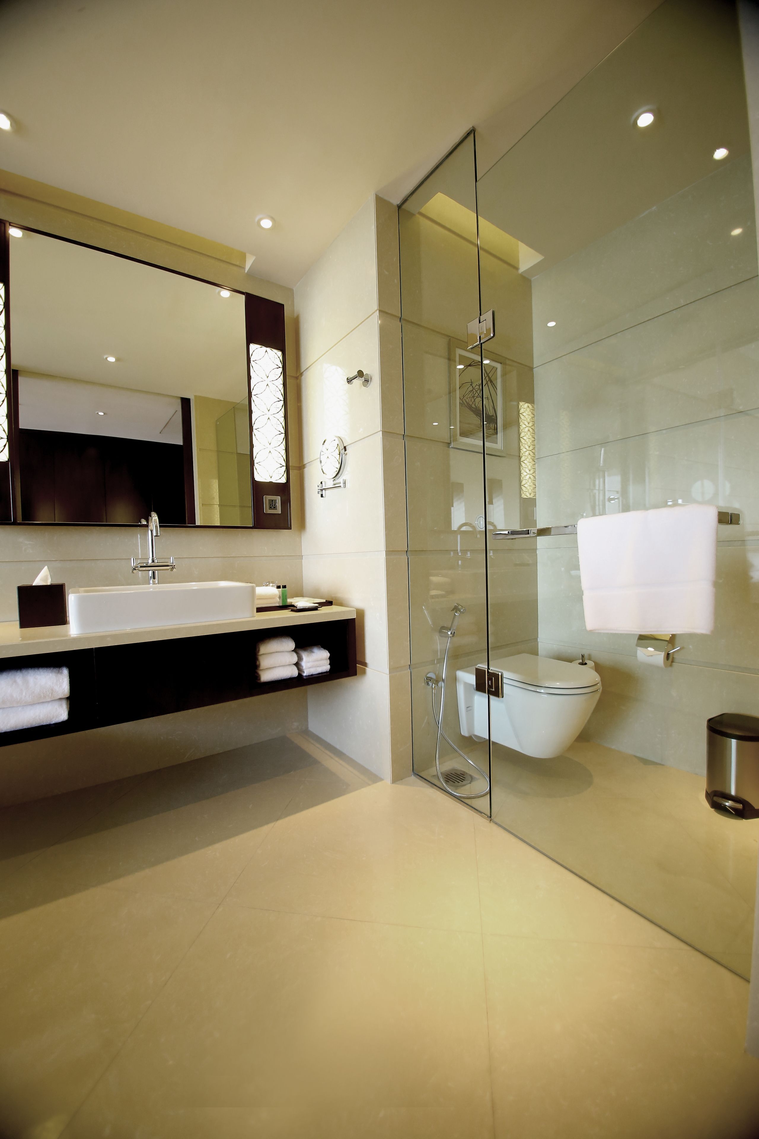 Un baño moderno con un espejo grande, un lavabo y una zona de ducha con cerramiento de cristal.