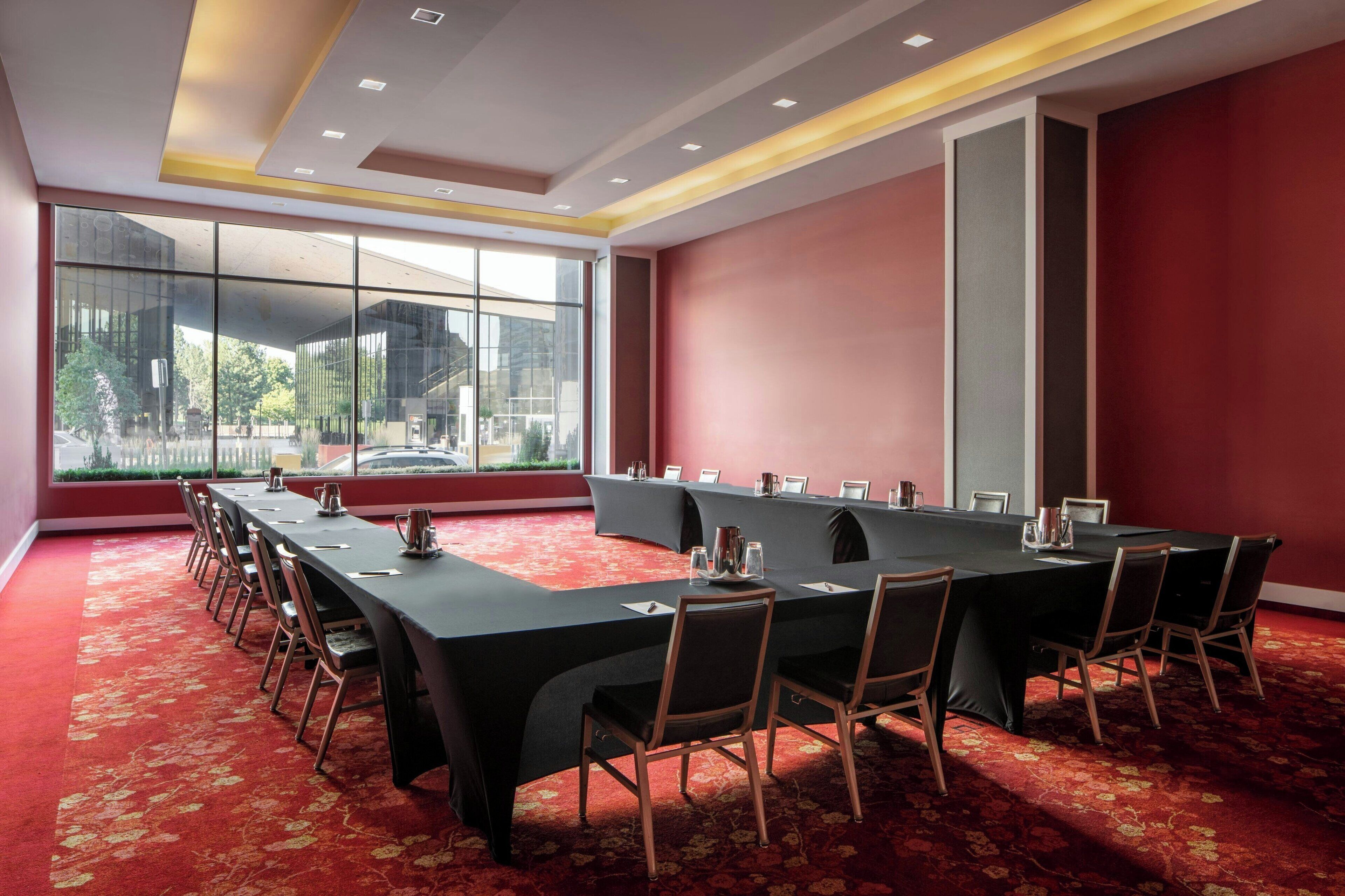 Un salón de conferencias con una larga mesa, sillas y una alfombra roja.
