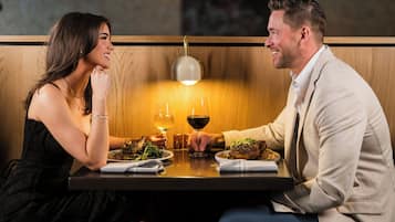 A couple dining at a restaurant with a wooden interior and pendant lighting.