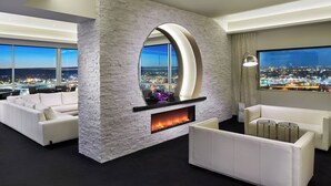 A modern living room with a fireplace, white sofas, and a large window offering a city view. - The Davenport Grand, Autograph Collection (Spokane)