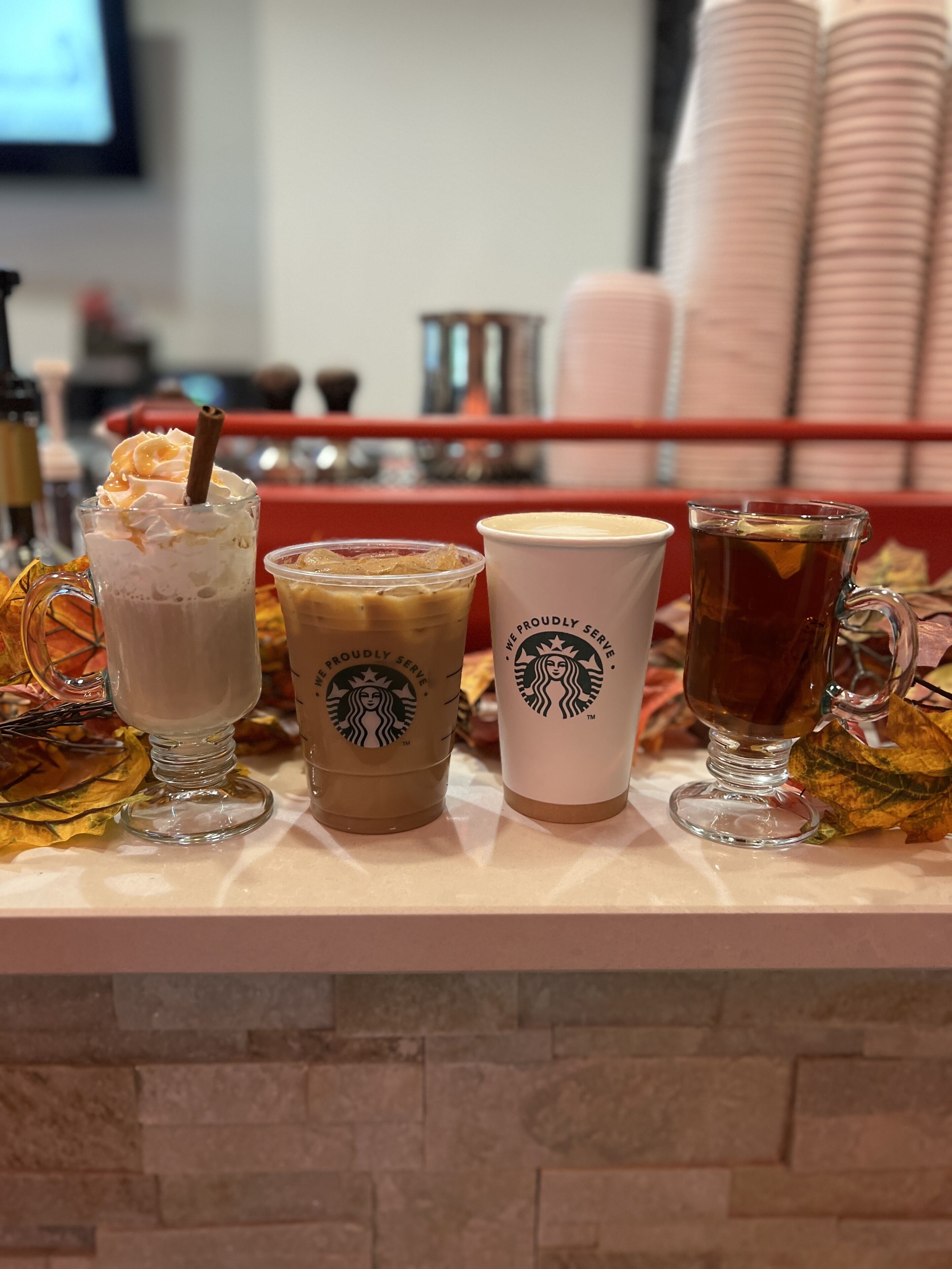 Eine Theke mit drei Starbucks Getränken und einem Teeglas.