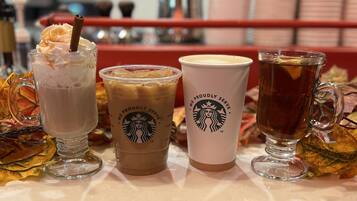 Eine Theke mit drei Starbucks Getränken und einem Teeglas.