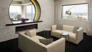 A modern living room with a large round mirror, a piano, and a sofa with patterned cushions. - The Davenport Grand, Autograph Collection (Spokane)