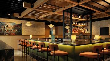 A bar area with a long counter, multiple stools, and a variety of bottles and glasses.