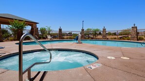Una piscina con hidromasaje, sillas de descanso y una fuente de piedra.