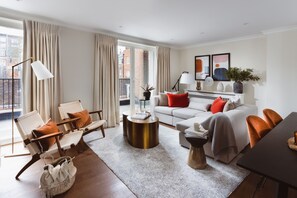 A modern living room with a sofa, chairs, a coffee table, and a dining table. - Native Mayfair (London)