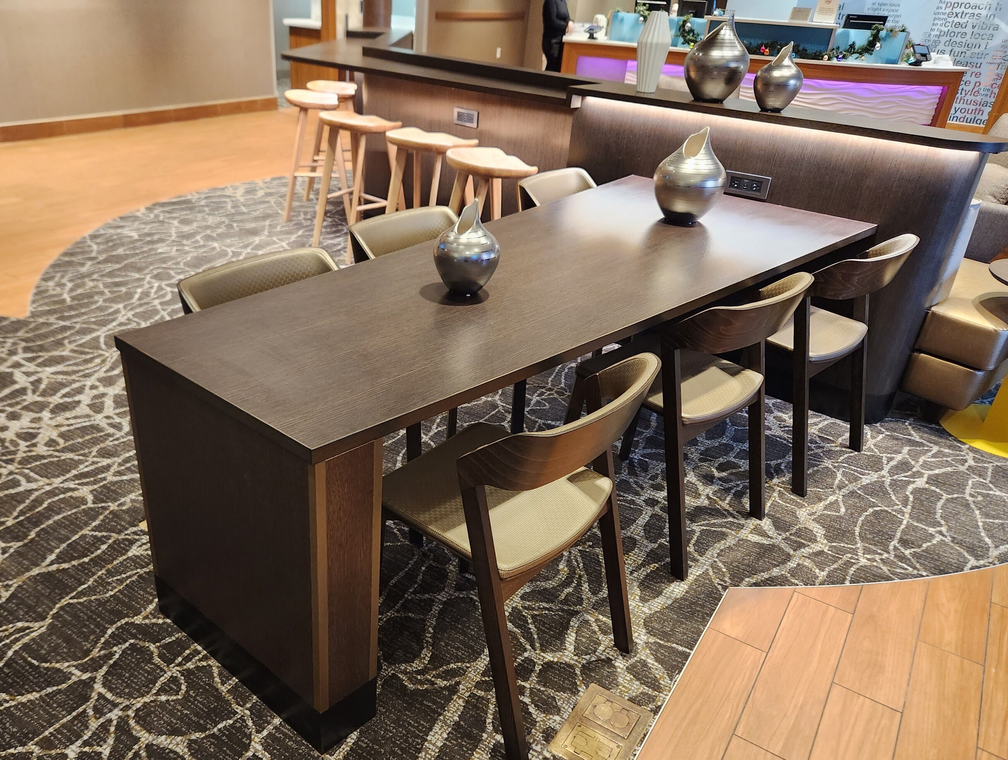 A dining area with a dark wooden table, cushioned chairs, and decorative vases.
