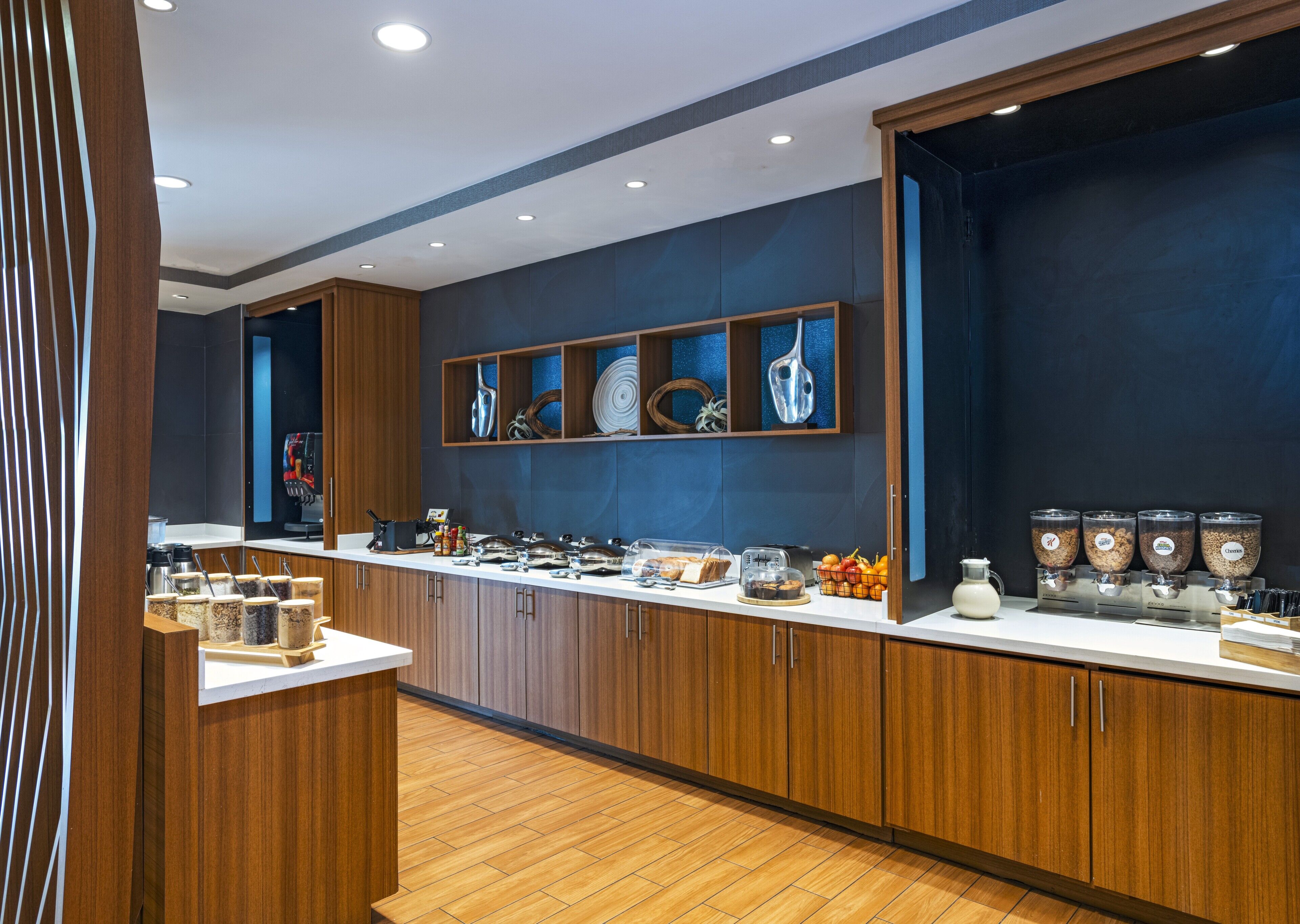 Una cocina moderna con armarios de madera, encimera blanca y diversos alimentos y utensilios.