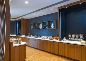 Une cuisine moderne avec des meubles en bois, un plan de travail blanc et une variété d’aliments et d’ustensiles de cuisine.