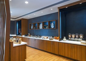Una cocina moderna con armarios de madera, encimera blanca y diversos alimentos y utensilios.
