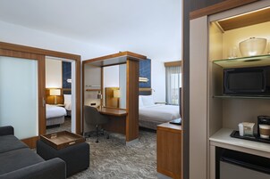 Una habitación de hotel con cama, escritorio, silla, televisor y cafetera.