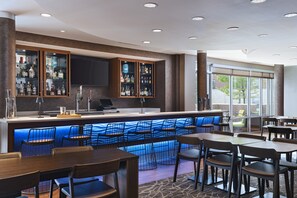 Un espace bar avec un comptoir, des sièges et une vue sur l’extérieur.
