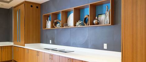 A modern kitchen with wooden cabinets, a white countertop, and decorative items on shelves.