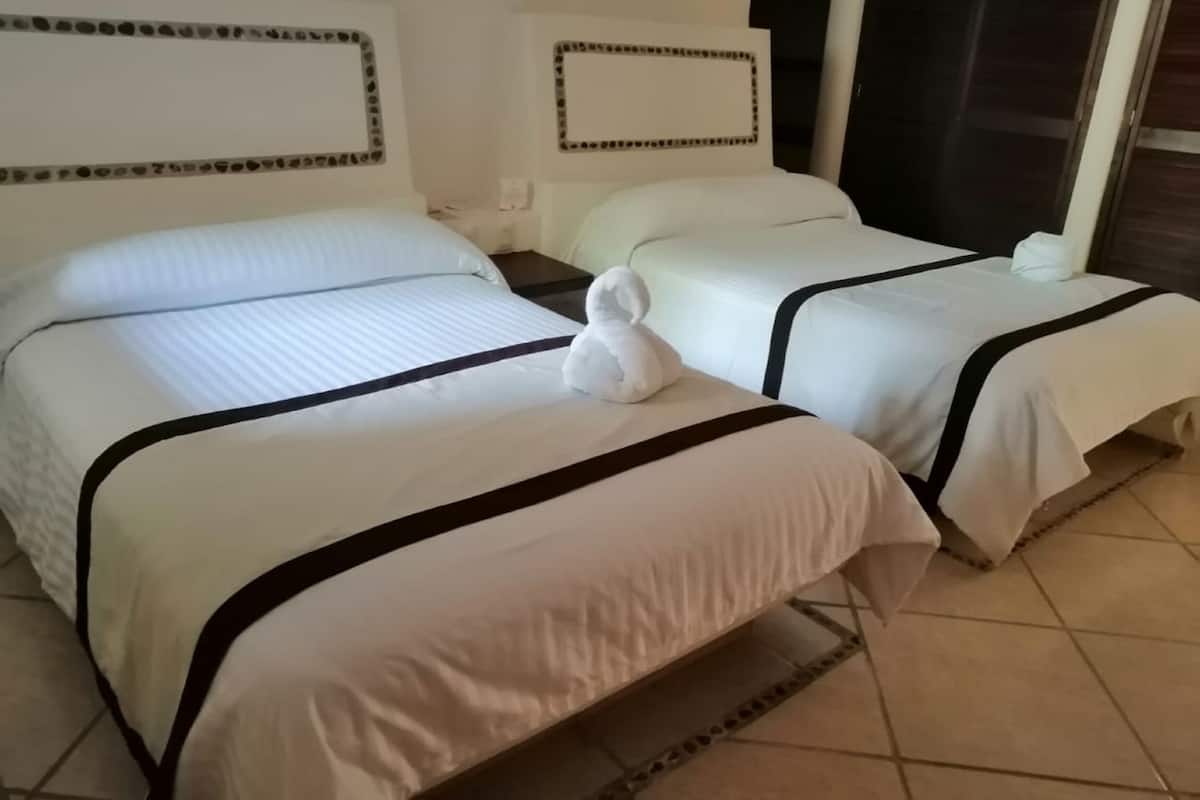 A hotel room with two beds, each with white bedding and black trim.
