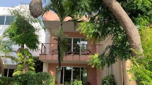 A two-story building with a balcony, surrounded by various plants and trees. - Villas Bakalar (Bacalar)