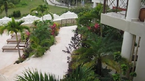 A resort balcony with a view of the ocean, palm trees, and a pathway leading to the beach. - Villas Bakalar (Bacalar)