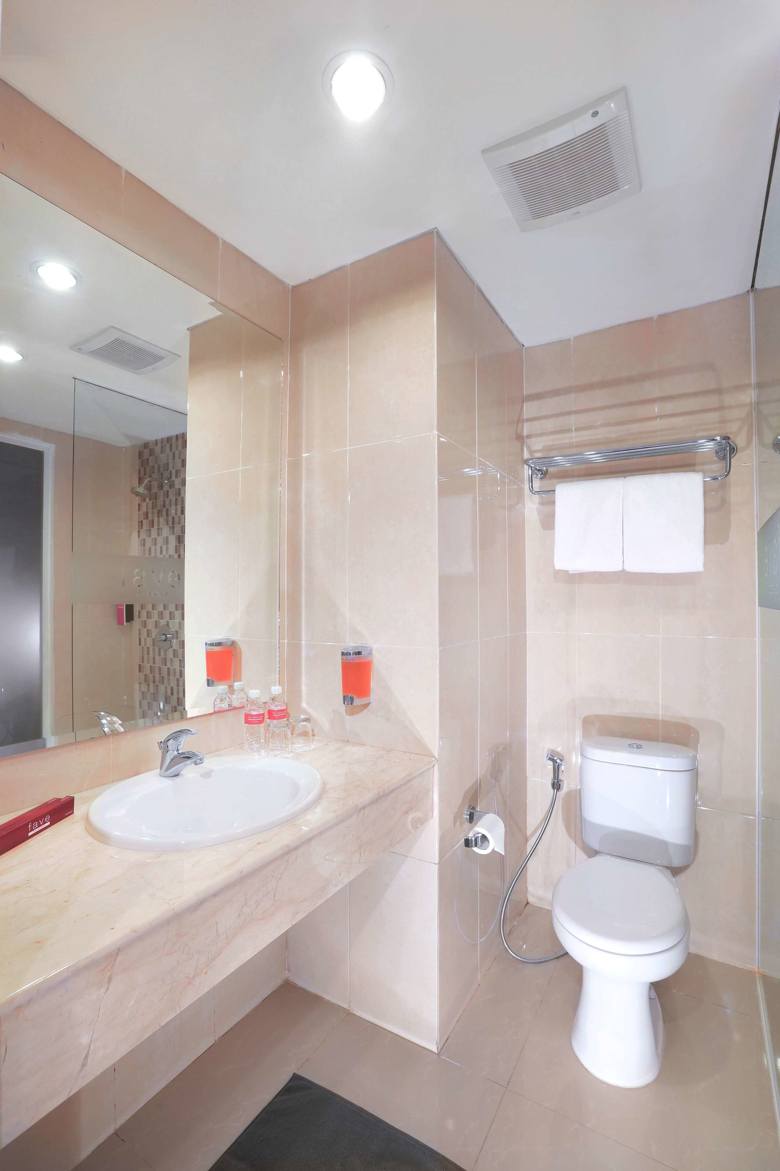 Une salle de bain moderne avec un grand miroir, deux lavabos, des toilettes et un espace douche.
