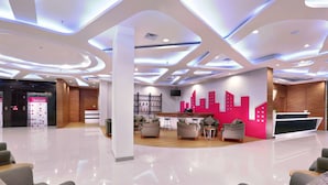 A modern hotel lobby with a reception desk, seating area, and a display of amenities. - favehotel Jababeka Cikarang (Cikarang)