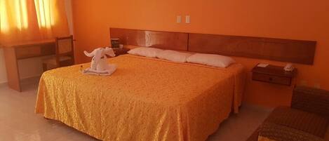 Una habitación de hotel con una cama grande, un cabecero de madera, una mesita de noche y una pequeña mesa.