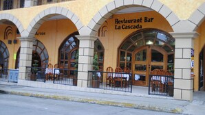A restaurant with a yellow facade and arched windows. - Hotel Arcos del Parque (Acayucan)