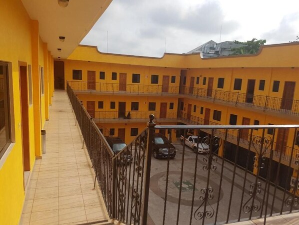 Un edificio amarillo de varios pisos con balcones y un patio interior.