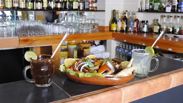 A bar counter with a variety of bottles and glasses. - Hotel Arcos del Parque (Acayucan)