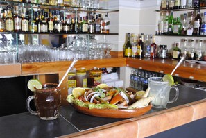 A bar counter with a variety of bottles and glasses. - Hotel Arcos del Parque (Acayucan)