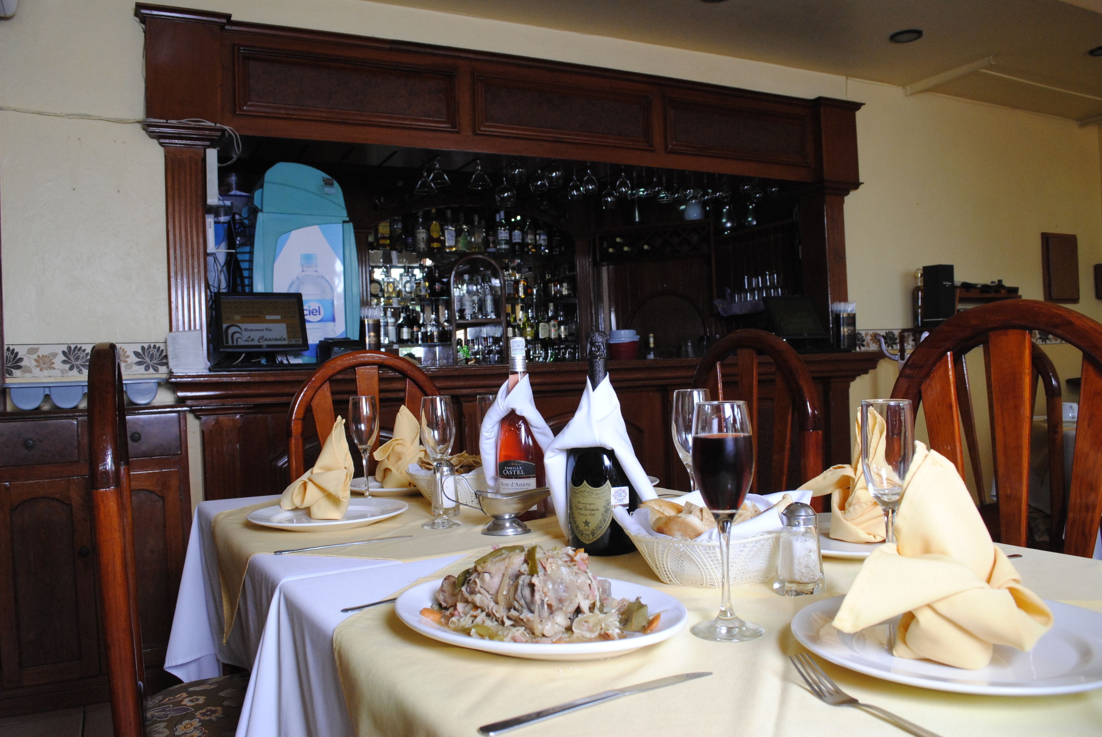 Una mesa de comedor dispuesta con platos de comida, copas de vino y una botella.