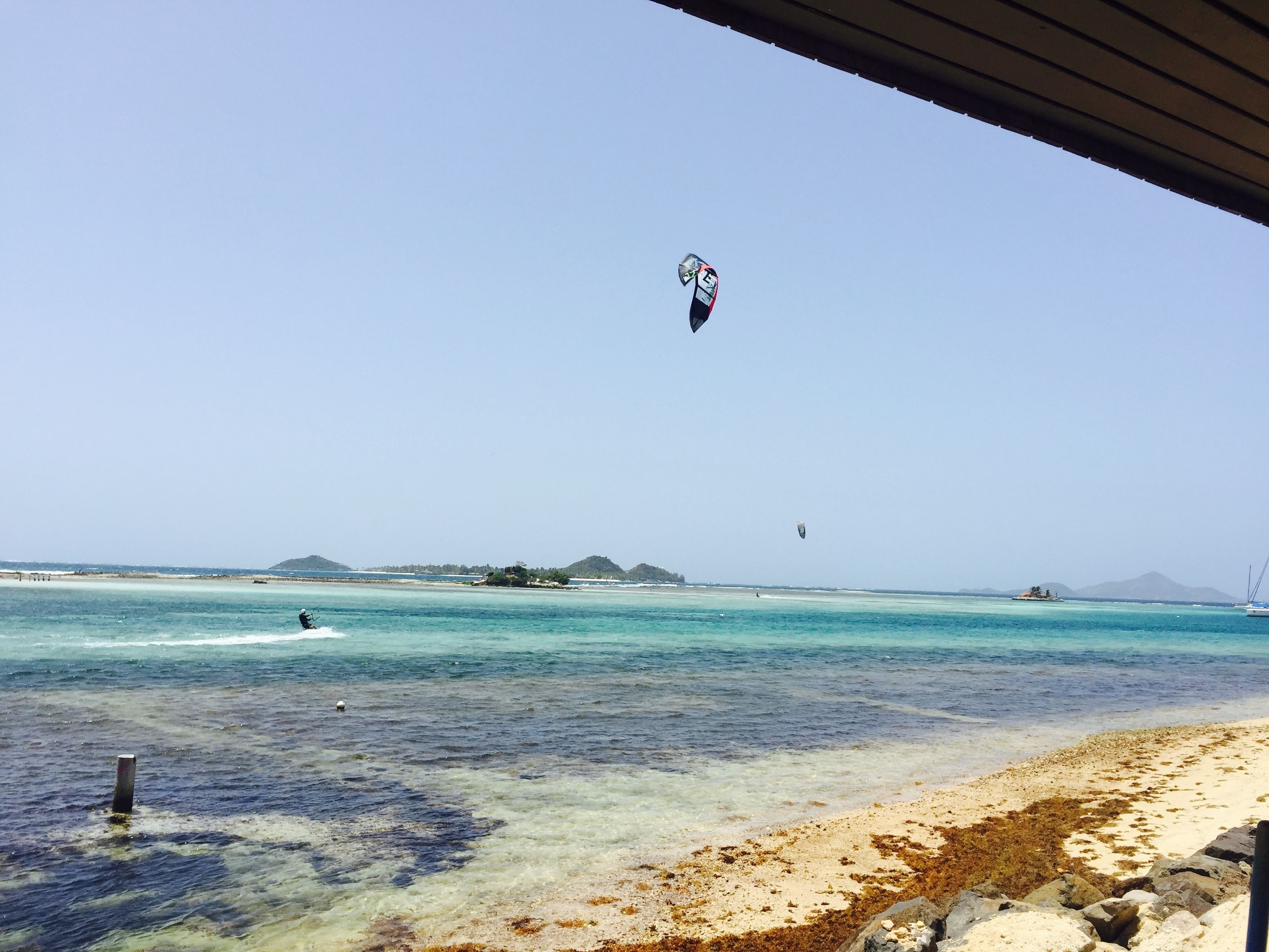 A beach with clear turquoise waters, a sandy shore, and distant islands.