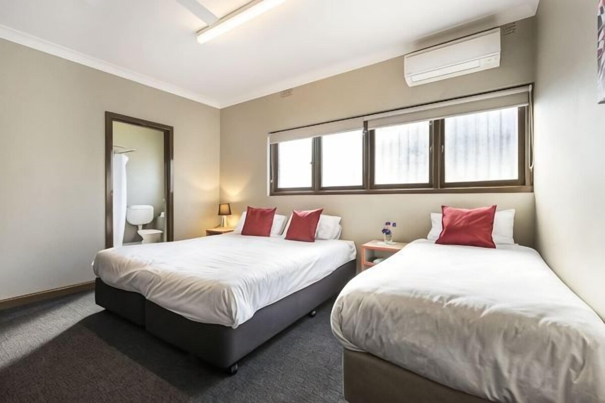 A hotel room with two beds, a window, a nightstand, and a mirror.