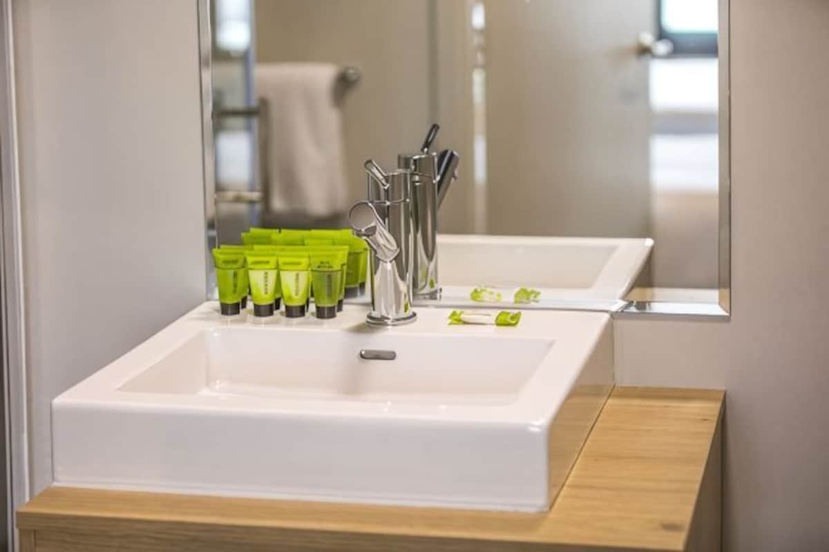 A bathroom with a white sink, green toiletries, and a mirror.