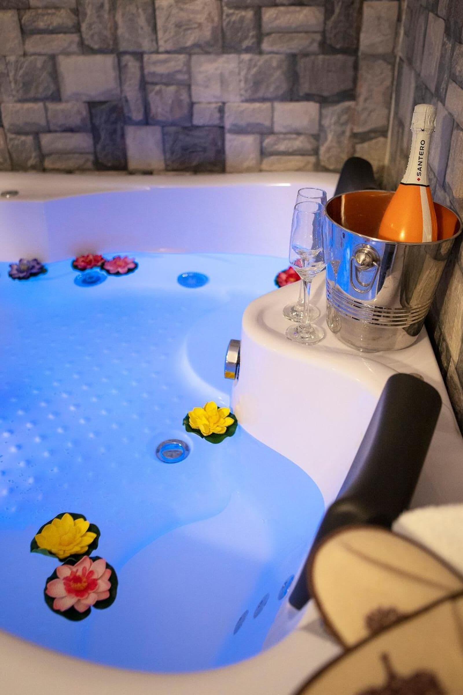 Une baignoire décorée de fleurs, une bouteille de champagne et un verre.