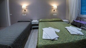 A hotel room with two beds, a small table, and two wall-mounted lamps. - Casa Barberini (Rome)