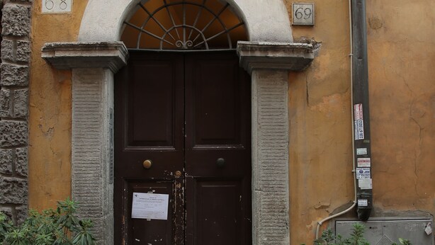 A building with a dark brown double door, numbers 68 and 69, and two potted plants on either side. - Casa Barberini (Rome)