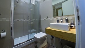 A modern bathroom with a glass-enclosed shower, a white toilet, and a wooden vanity with a sink. - Casa Barberini (Rome)