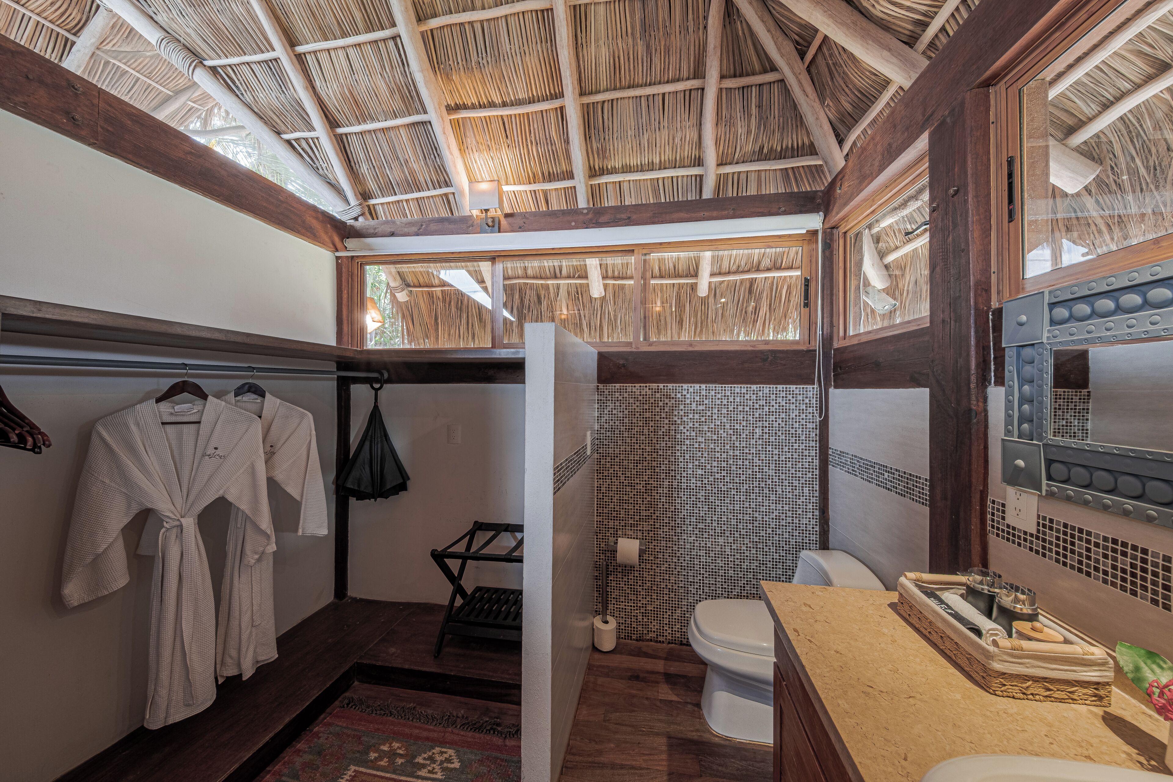 A bathroom with a wooden ceiling, a toilet, a sink, and a towel rack.