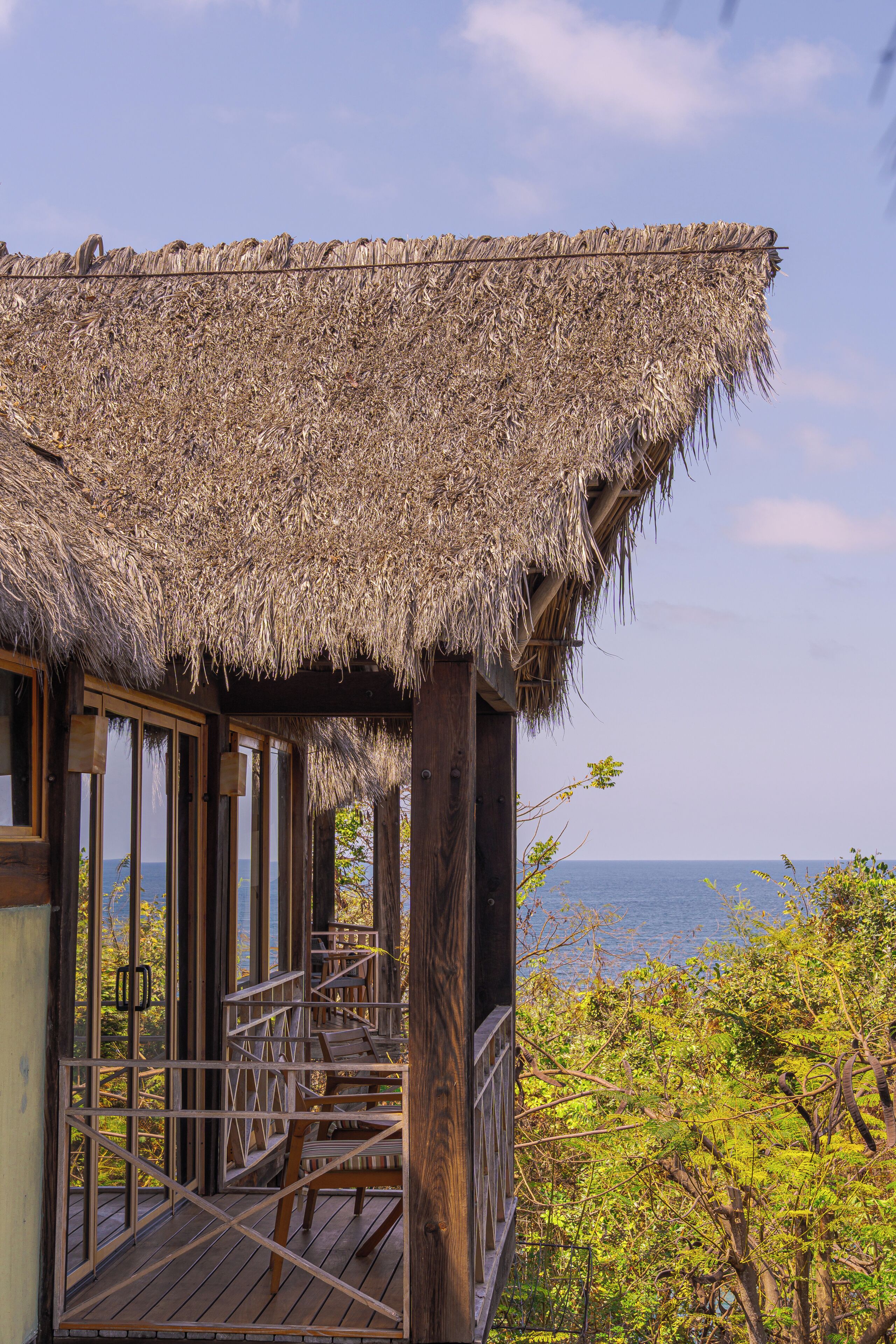 A wooden structure with a thatched roof, wooden railings, and a view of the sea.