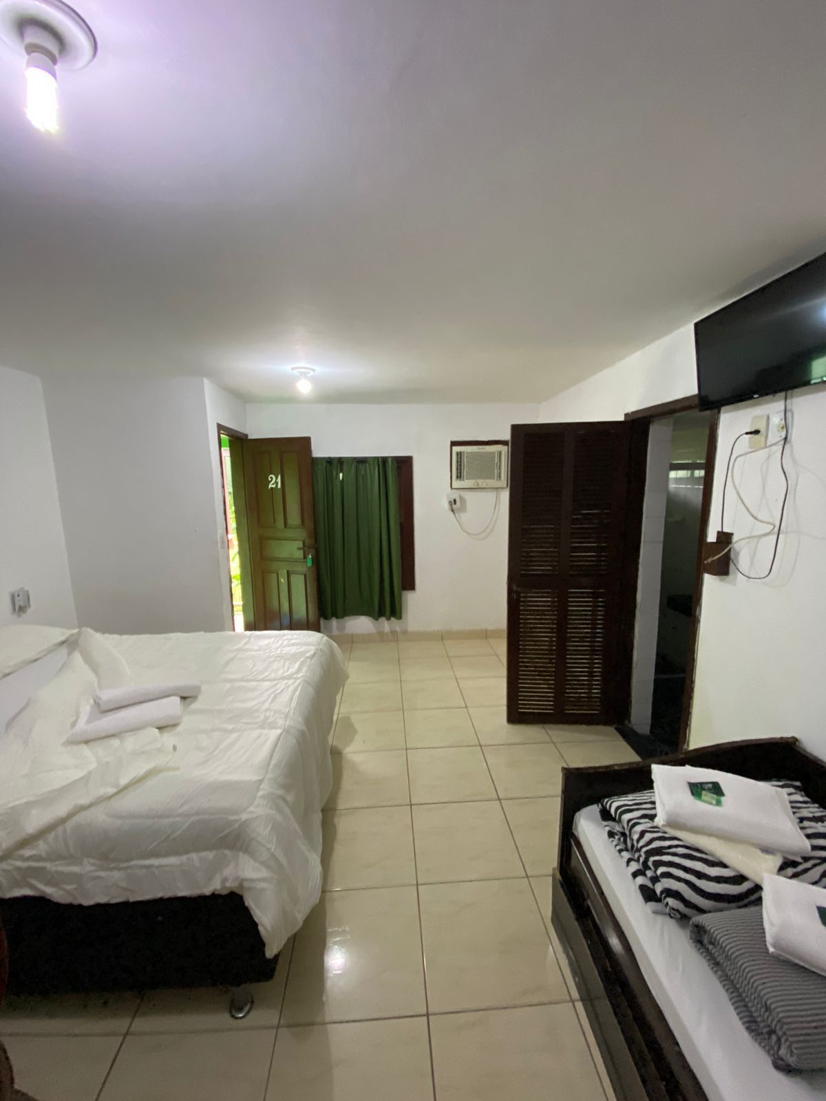Een hotelkamer met een bed, een bank, een televisie en een airconditioner.