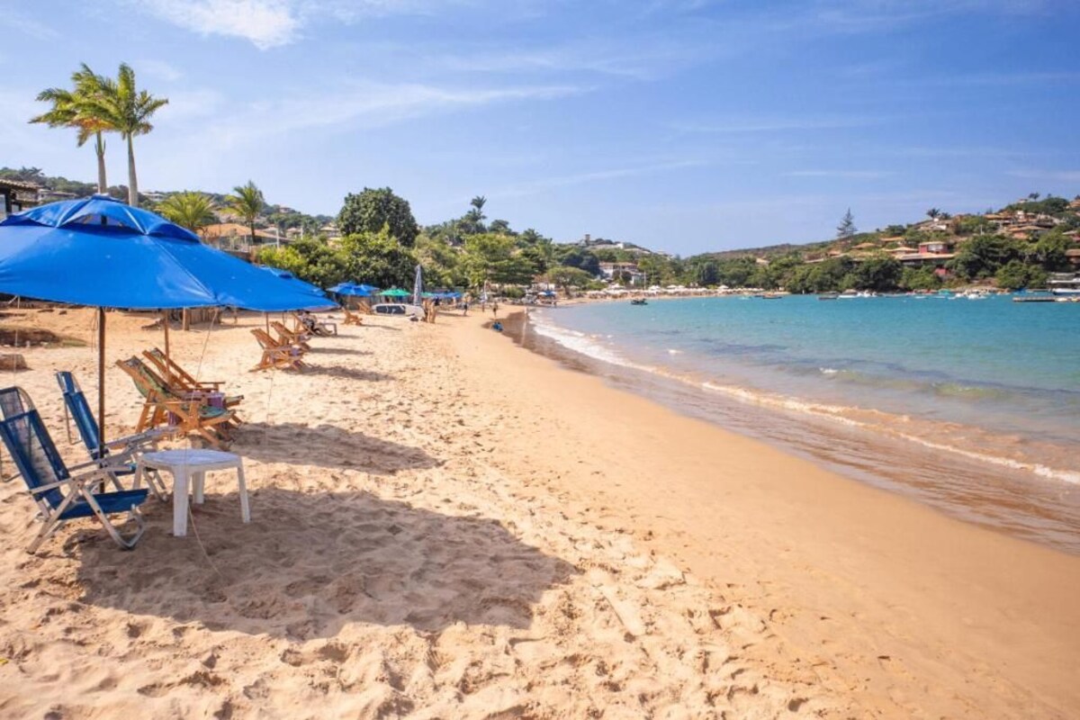 A beach with sun loungers and umbrellas, a clear sky, and a calm sea.