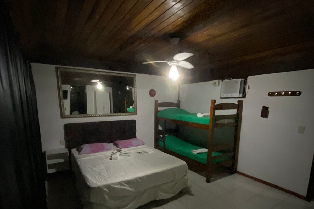 A room with a bed, a mirror, a ceiling fan, a heater, and a bunk bed.