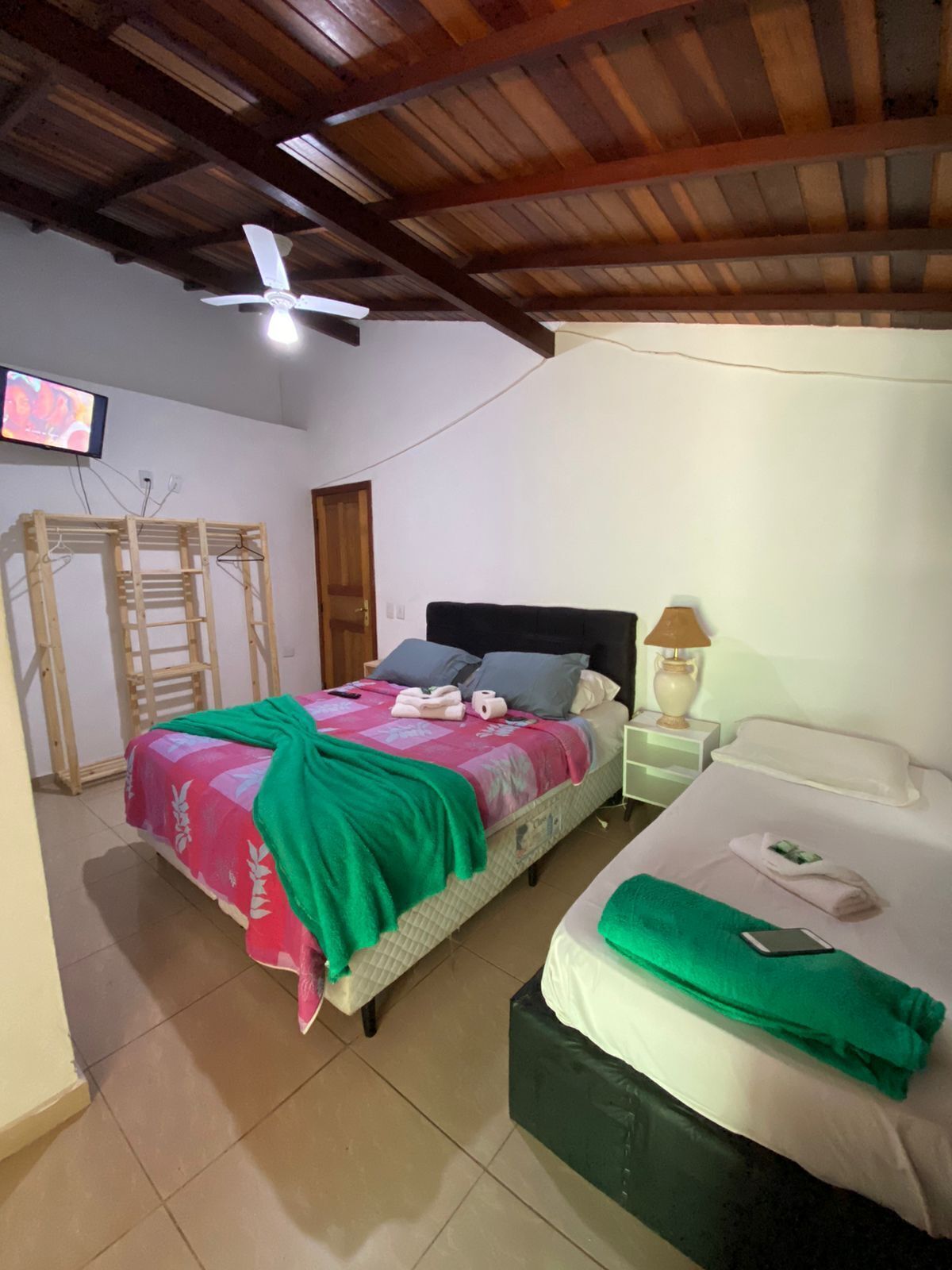 Een slaapkamer met twee bedden, een plafondventilator, een televisie en een houten trap.