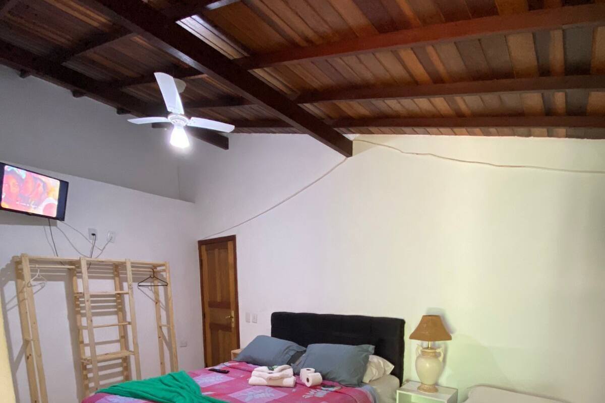 A bedroom with two beds, a ceiling fan, a TV, and a wooden ladder.