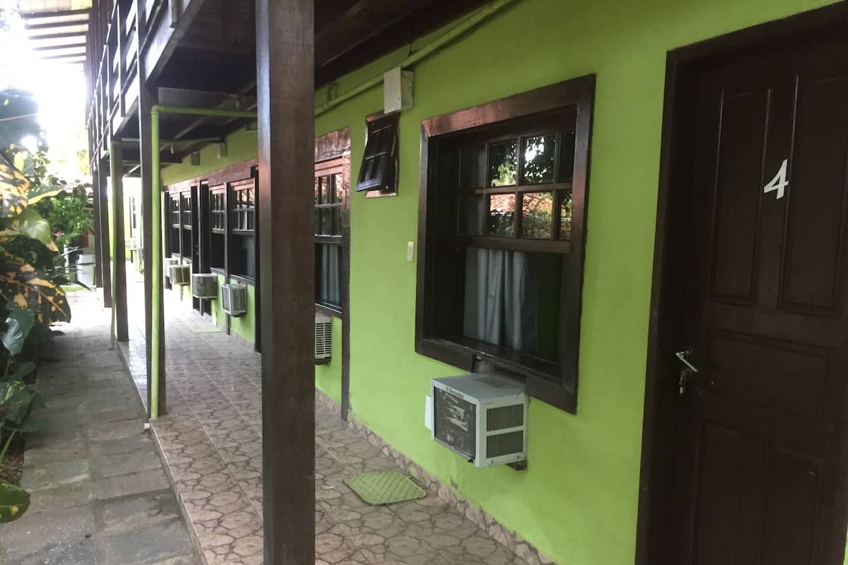 A corridor with green walls, tiled flooring, and multiple air conditioning units.