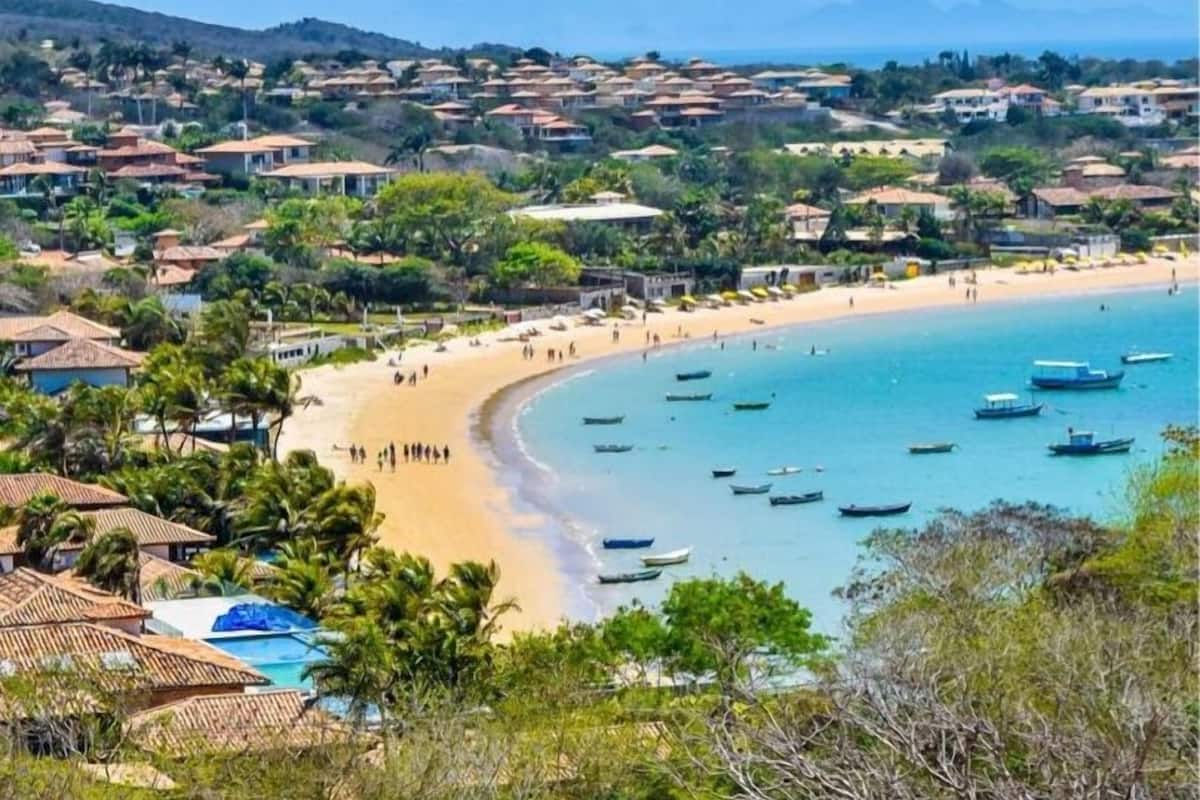 A coastal town with a beach, boats, and houses with red roofs.
