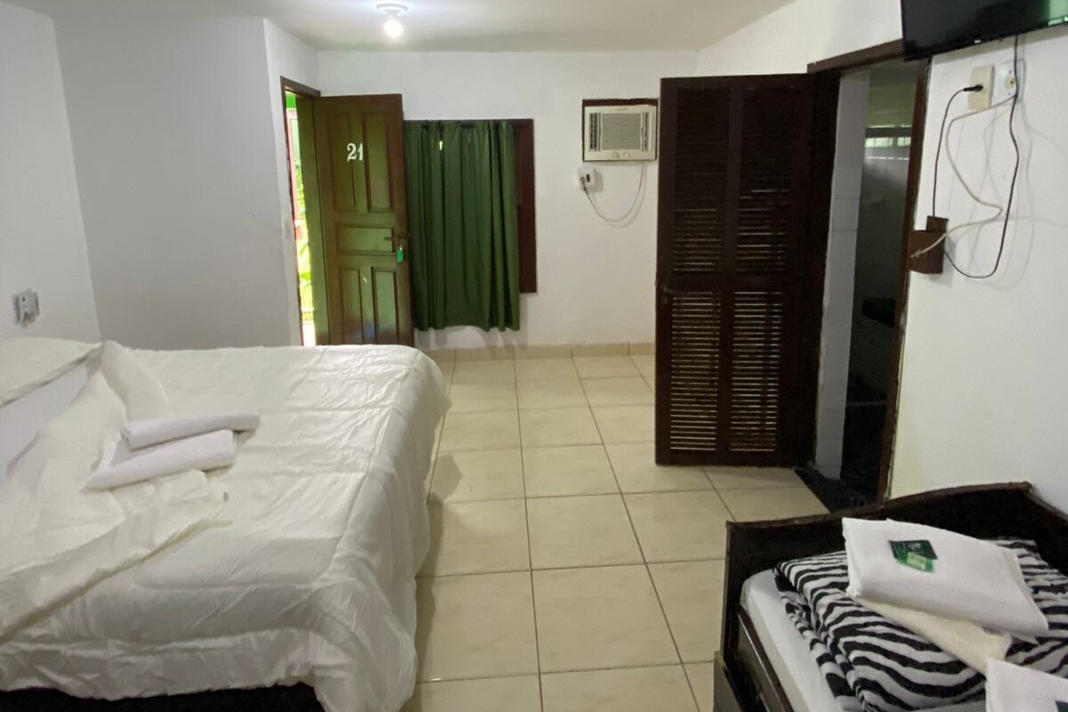 Een hotelkamer met een bed, een bank, een televisie en een airconditioner.