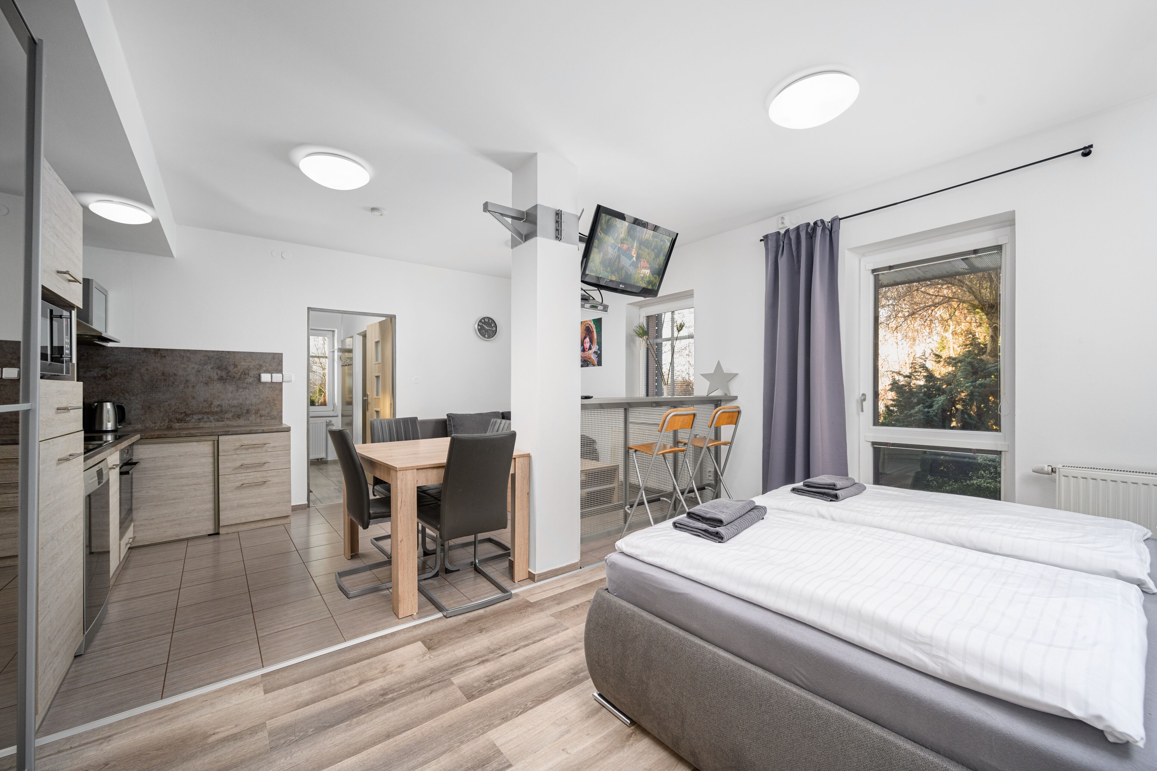 Ein modernes Zimmer mit Bett, Schreibtisch und einer Küchenzeile.