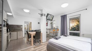 Ein modernes Zimmer mit Bett, Schreibtisch und einer Küchenzeile.