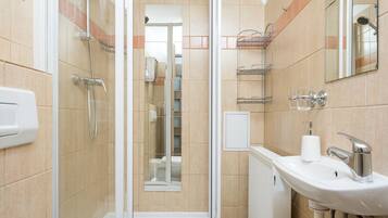 Un baño moderno con ducha de vidrio, un lavamanos blanco y un inodoro.